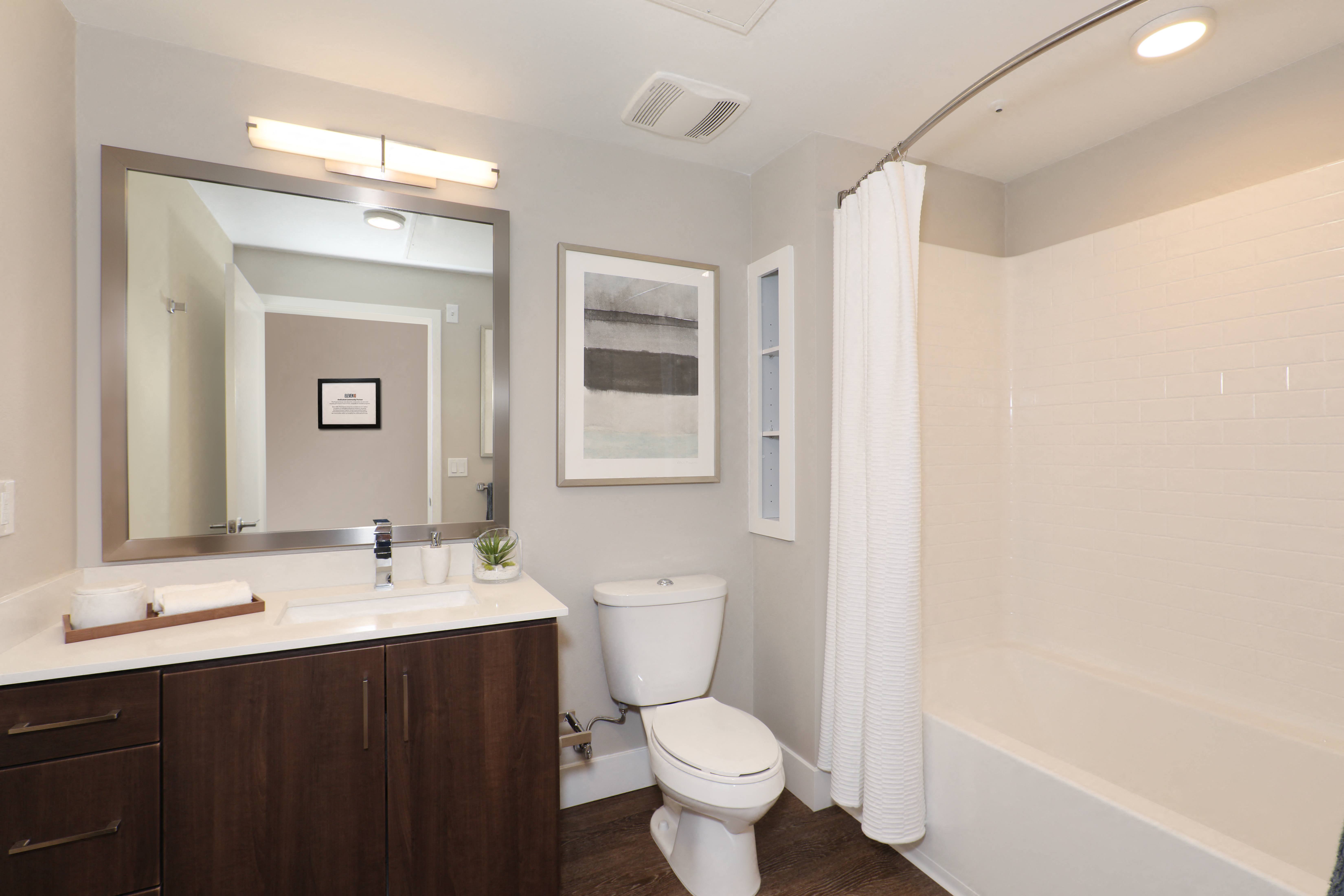 Modern bathroom featuring a toilet, sleek sink, mirror, and a spacious shower.